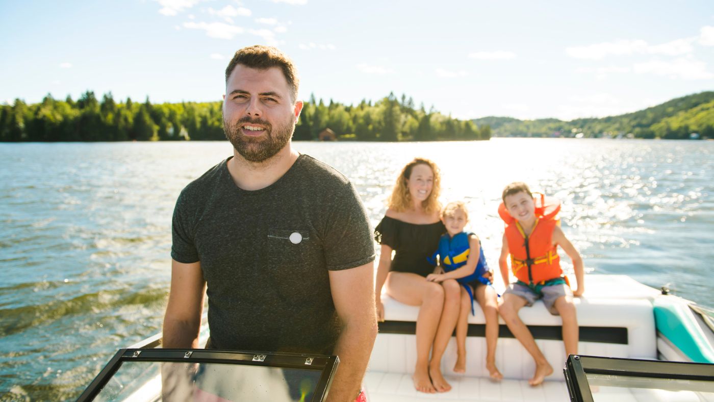 A family with two young children wearing lifejackets taking a ride in a motorboat.